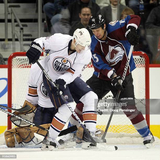 Ladislav Smid of the Edmonton Oilers and Chris Stewart of the Colorado Avalanche battle for position as the puck finds a path to the goal on a shot...
