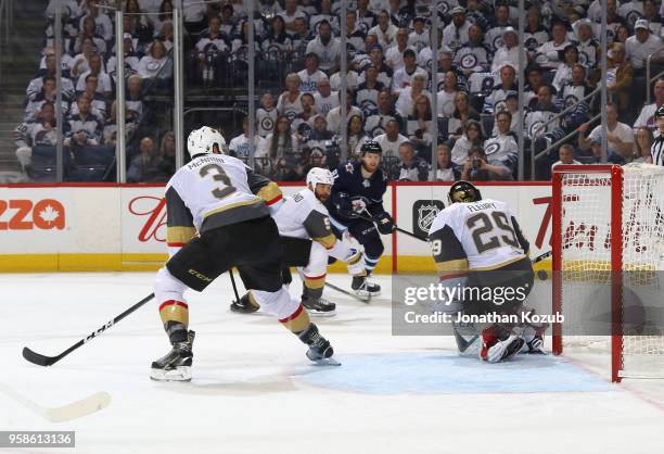 Brayden McNabb, Deryk Engelland of the Vegas Golden Knights and Kyle Connor of the Winnipeg Jets watches as the puck gets behind goaltender...