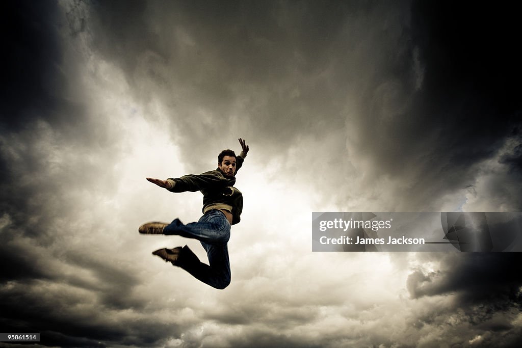 Young boy Jumping with dramatic clouds