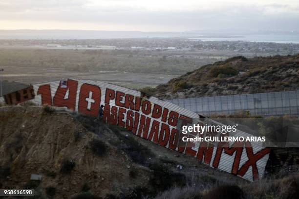 Painting reading in Spanish "140 periodistas asesinado en MX" is seen at a US/Mexico border fence section in Tijuana, Baja California State, Mexico,...
