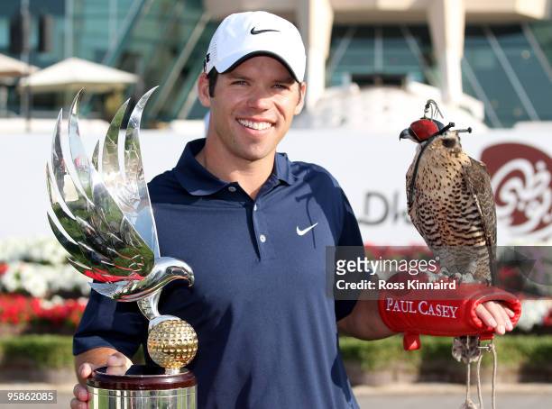 Paul Casey of England, the defending champion, poses for a photograph alongside the trophy with a falcon on his arm in front of the clubhouse during...