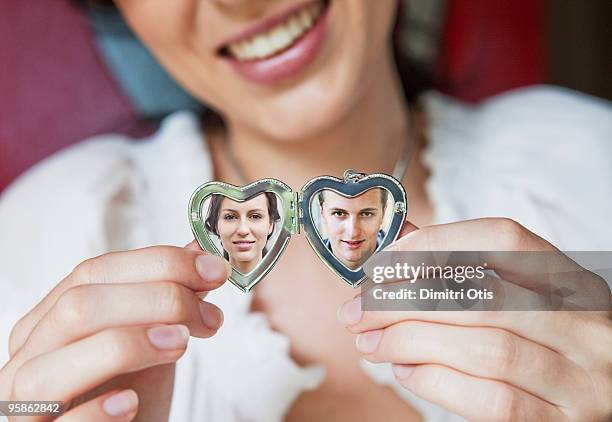 woman showing her boyfriend in locket - heart locket stock-fotos und bilder