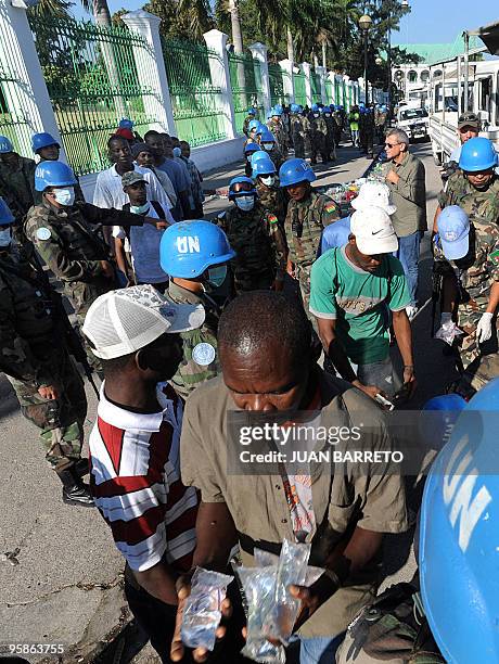 Locals line up to receive water distributed by Bolivian UN forces on January 17, 2010 in Port-au-Prince, five days after a massive earthquake...