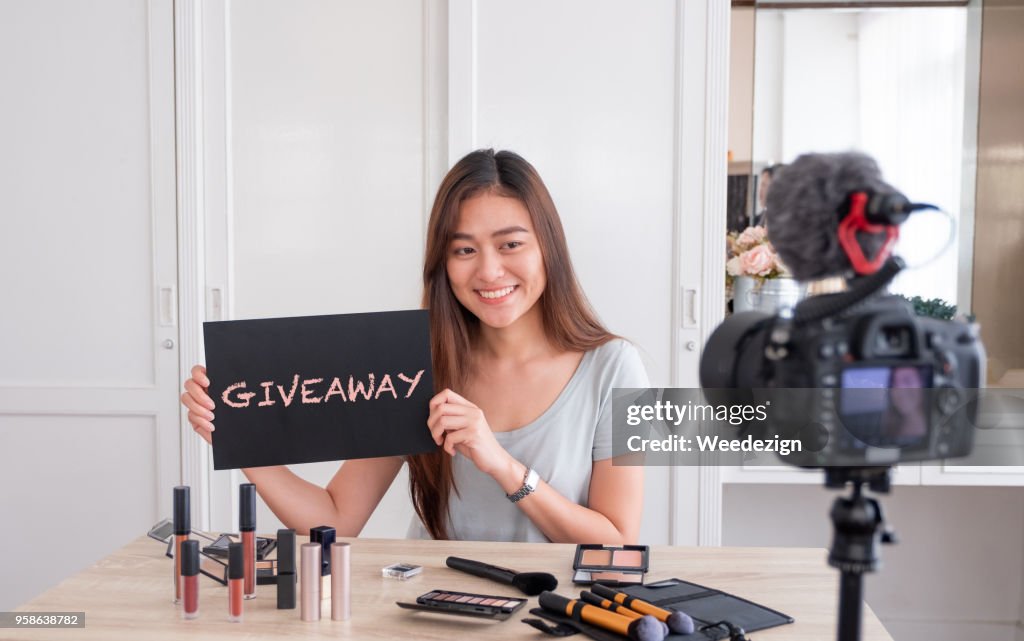 Regalo de sorteo de blogger femenina joven asiático siguiente ventilador canal mientras que grabación vlog video con cosmética de maquillaje en casa online influyente en redes sociales streaming concept.live viral.