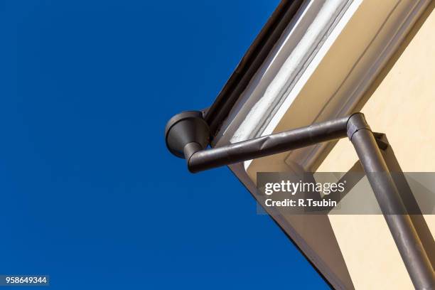 rain gutters on old home. there is a blue sky in the background. - overhangende rots stockfoto's en -beelden