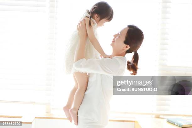 mother lifting baby girl - korean baby girl stock-fotos und bilder