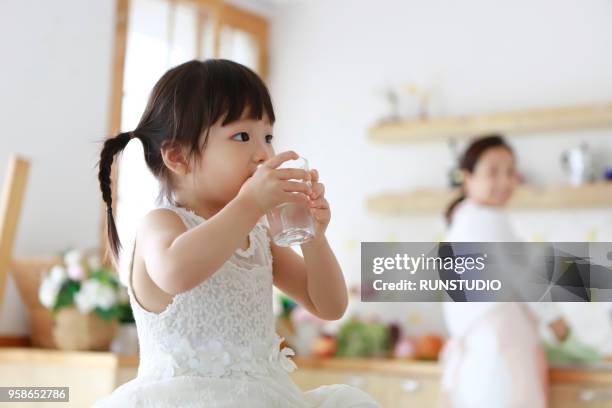 little girl drinking glass of water in kitchen - korean teen stock pictures, royalty-free photos & images