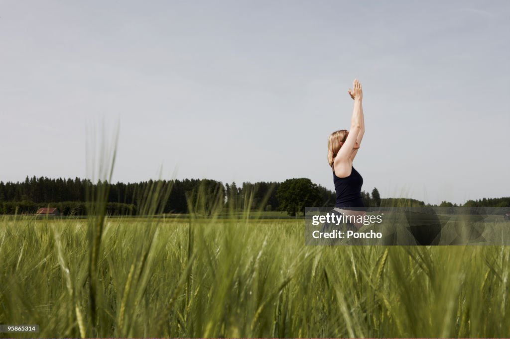 Pregnant woman in yoga position in corn field