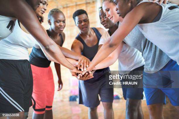 basketball players stacking hands together in gym - basketball team stock pictures, royalty-free photos & images