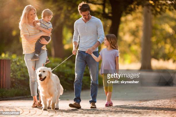 glückliche familie sprechen während des gehens mit einem hund im frühling. - family dog stock-fotos und bilder