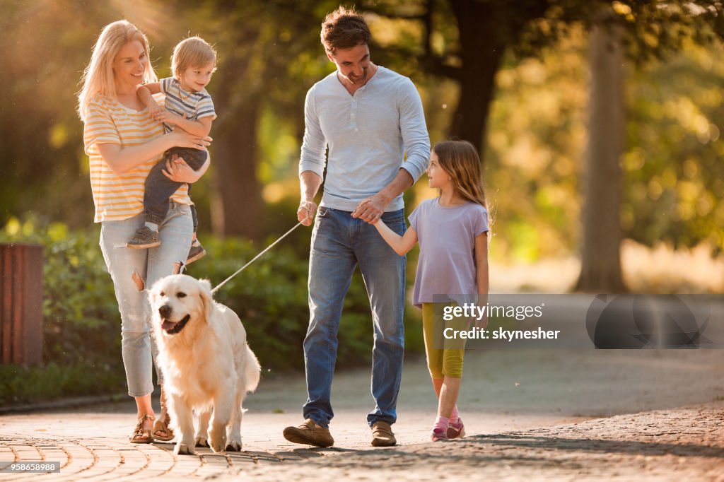 Happy family talking while walking with a dog in spring day.