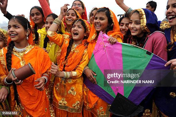 Indian school girls, dressed in outfits of the Punjabi traditional folk dance, the Giddha watch kites flying on the eve of Basant Panchami, the...