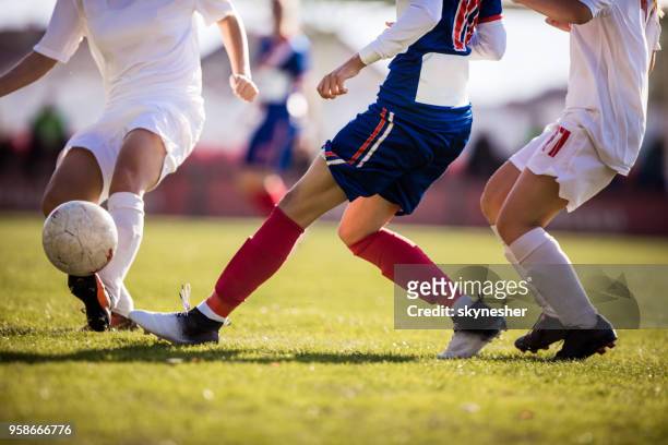 onherkenbaar voetbalspeler met bal op een wedstrijd terwijl het vermijden van haar tegenstander. - tackling stockfoto's en -beelden