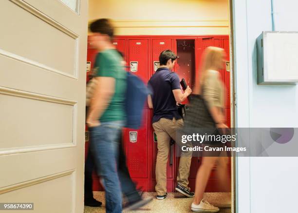 rear view of man removing books from locker - high school building entrance stock pictures, royalty-free photos & images