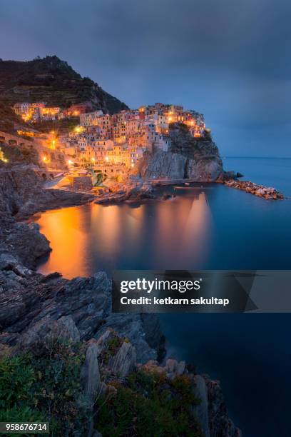 illuminated famous manarola at dusk, la spezia, linguria, italy. - linguria stock pictures, royalty-free photos & images