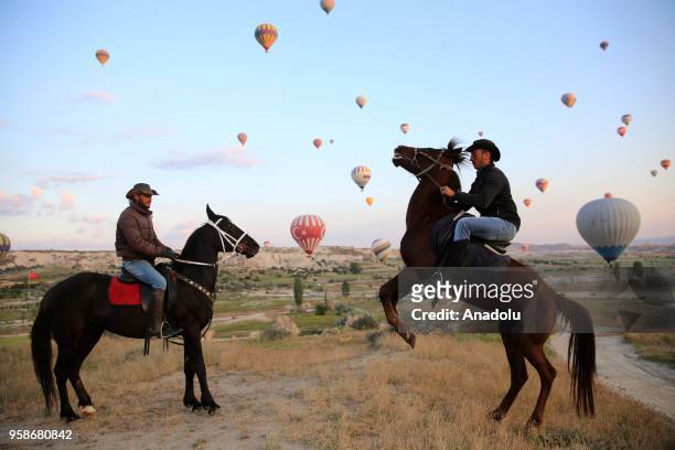 Men ride horses among hot air balloons near fairy chimneys in Cappadocia in Turkey's Nevsehir on May 14, 2018. Cappadocia known as "The Land of...