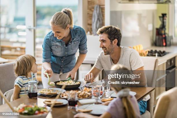 gelukkig jongedame lunch serveren aan haar familie aan de eettafel. - family dining stockfoto's en -beelden