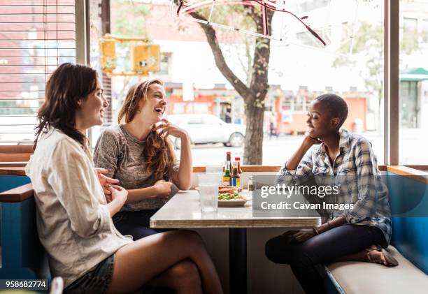 friends talking while sitting in restaurant - 3 people at table talking stock pictures, royalty-free photos & images