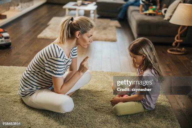 moeder scolding meisje op tapijt in de woonkamer. - berispen stockfoto's en -beelden