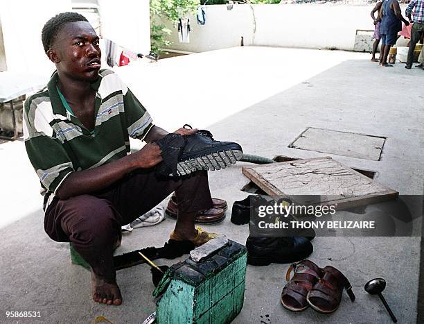 Haitian shoe shiner shines shoes for 20 cents a pair, 22 June 2001, in a slum in the coastal town of Cap-Haitien, Haiti, 101 miles north of...