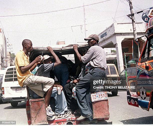 Haitians ride together in the back of a truck, the typical mode of public transportation, 10 July, 2003 in Port-Au-Prince, Haiti. The economy is in...