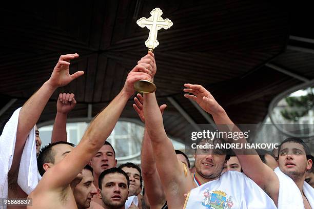 Twenty-two-years-old Nikola Gogic holds a golden cross after winning the race for the cross in the cold waters of the Danube river in Zemun near the...