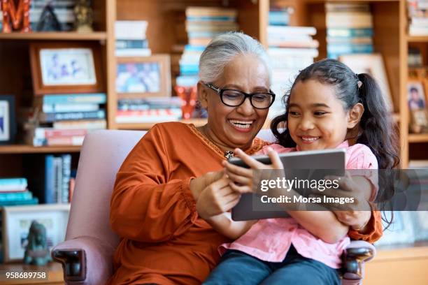 smiling females using digital tablet at home - malaysia family stock pictures, royalty-free photos & images