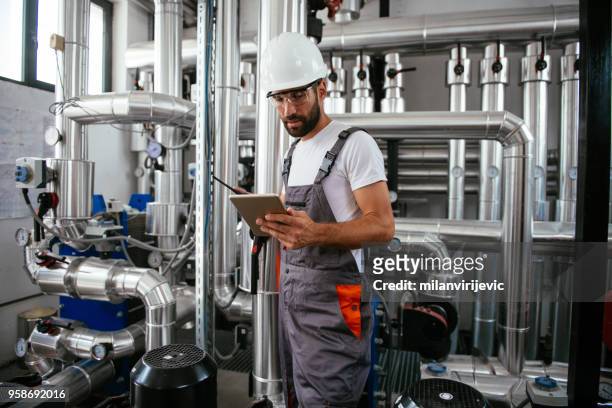 mann mit tablet bei erdgas verarbeitenden anlage - boiler engineer stock-fotos und bilder
