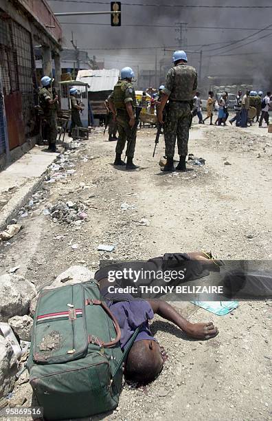 The body of a young student lies before United Nations Peacekeepers and a market reportedly set ablaze during disturbances 31 May 2005 in...