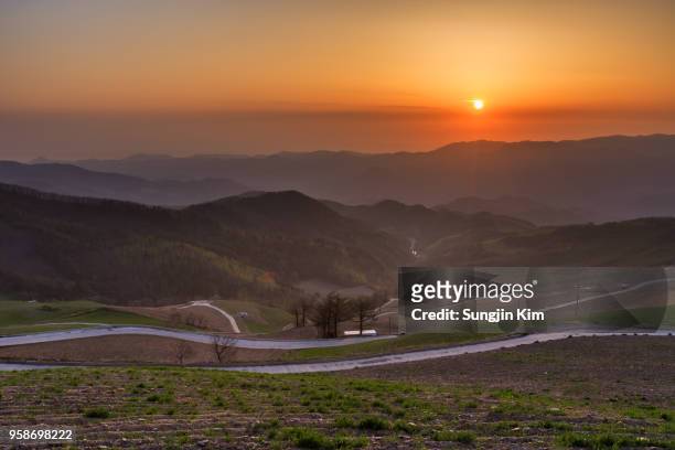 sunrise over the ridge of mountain viewed from the field - sungjin kim stock pictures, royalty-free photos & images