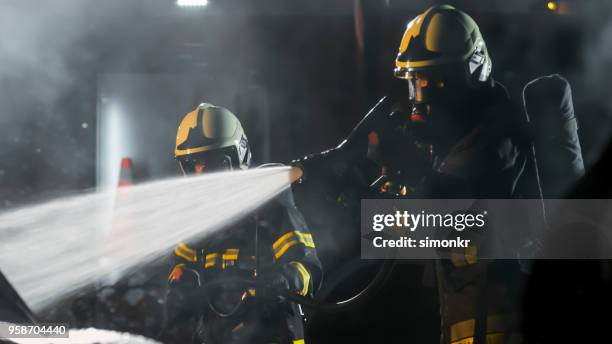 firefighters using extinguisher - fire hose through car stock pictures, royalty-free photos & images