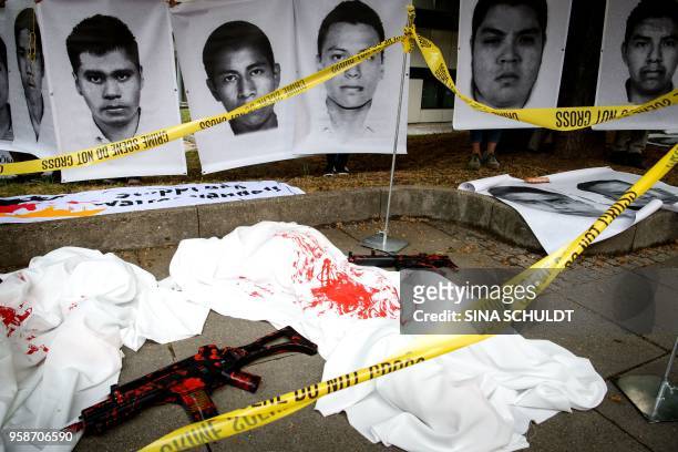 Demonstrators have set up a dummy weapon and portraits of Mexican students who have disappeared and probalby were killed in Mexico in the year 2014,...