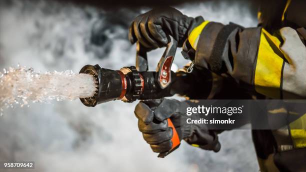 brandweerman met brandblusser - brandslang stockfoto's en -beelden