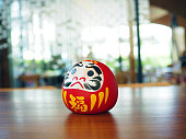 Daruma doll, a handmade Japanese doll symbolized of fortune or good luck place on wooden table.