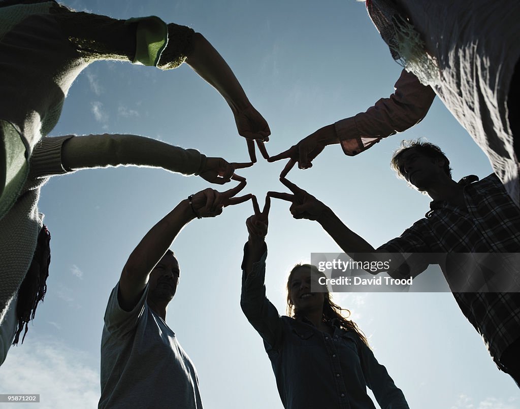 Group of people making a star with hands.