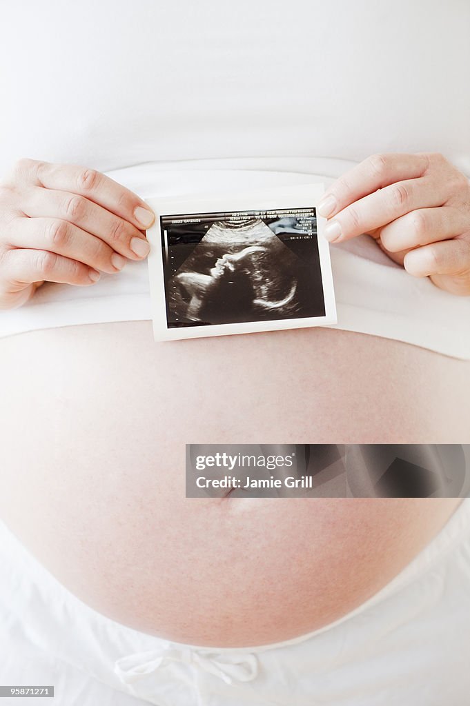 Pregnant woman holding ultrasound, close up