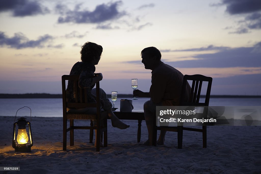 Couple having drinks on beach at sunset, Zanzibar