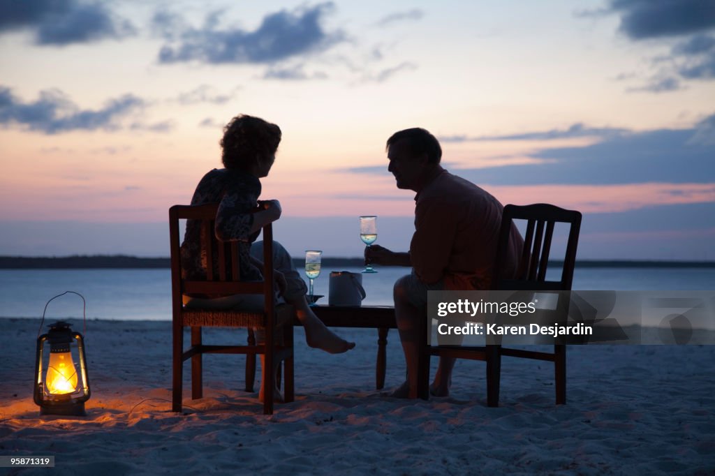 Couple having drinks on beach at sunset, Zanzibar