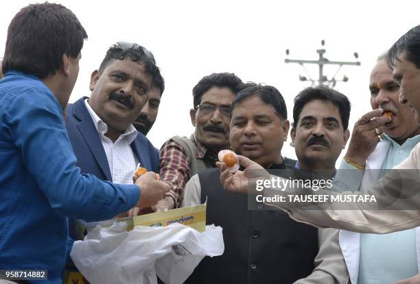 Workers from the ruling Bhartiya Janta Party celebrate outside the BJP office in Srinagar, after poll results in the Karnataka state assembly...