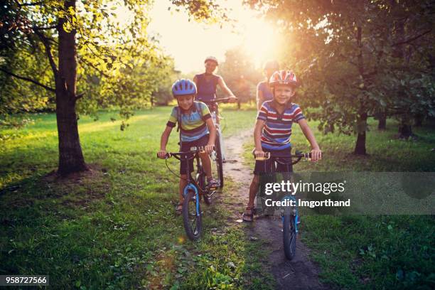 family riding bicycles in park - family biking stock pictures, royalty-free photos & images