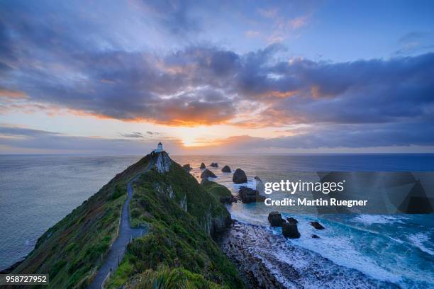 sunrise at nugget point lighthouse.  nugget point, the catlins, otago, otago coast, south island, new zealand, australasia, oceania. - nugget point stock pictures, royalty-free photos & images