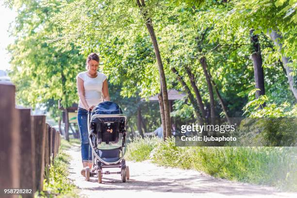 mother pushing daughter in stroller - baby stroller imagens e fotografias de stock