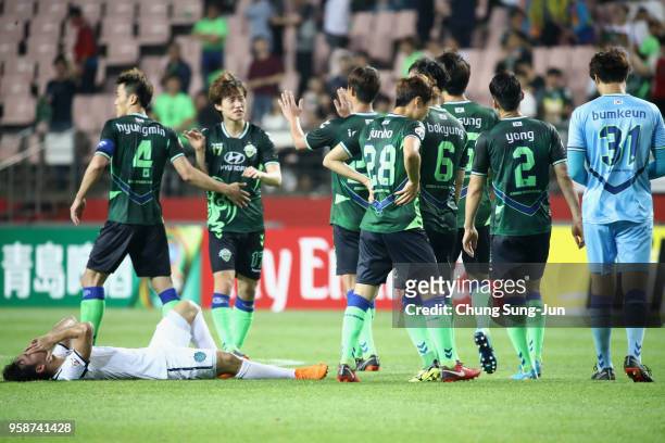 Supachok Sarachart of Buriram United shows dejection while Jeonbuk Hyundai Motors players celebrate their 2-0 victory and 4-3 aggregate win in the...