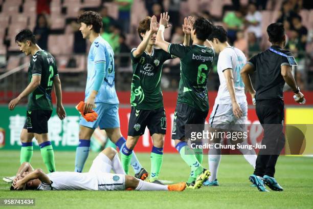 Supachok Sarachart of Buriram United shows dejection while Jeonbuk Hyundai Motors players celebrate their 1-0 victory and 4-3 aggregate win in the...