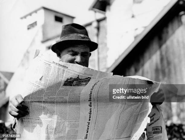 Mann liest eine zerfledderte Zeitung, 50er Jahre