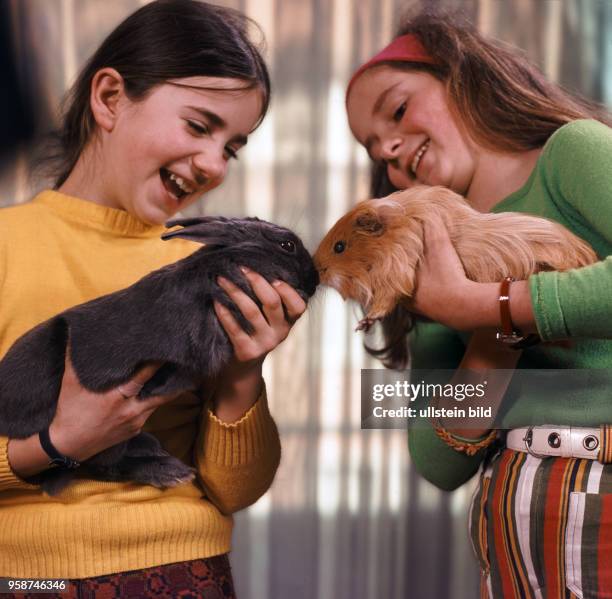 Zwei Mädchen präsentieren sich ihre Haustiere, 70er Jahre
