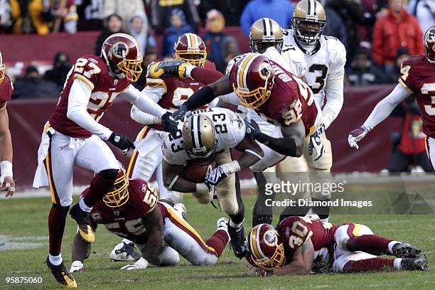 Running back Pierre Thomas of the New Orleans Saints is tackled by defensive back Fred Smoot and defensive lineman Brian Orakpo of the Washington...