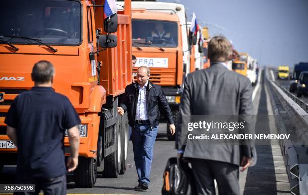 Russian President Vladimir Putin walks away from a construction truck after he drove the vehicle across the new 19 kilometres road-and-rail Crimean...