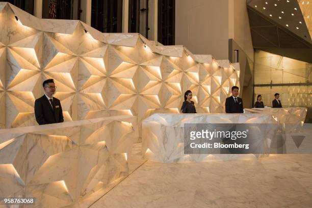 Workers stand behind desks in the main reception area of the Morpheus hotel, developed by Melco Resorts & Entertainment Ltd., during a media tour in...