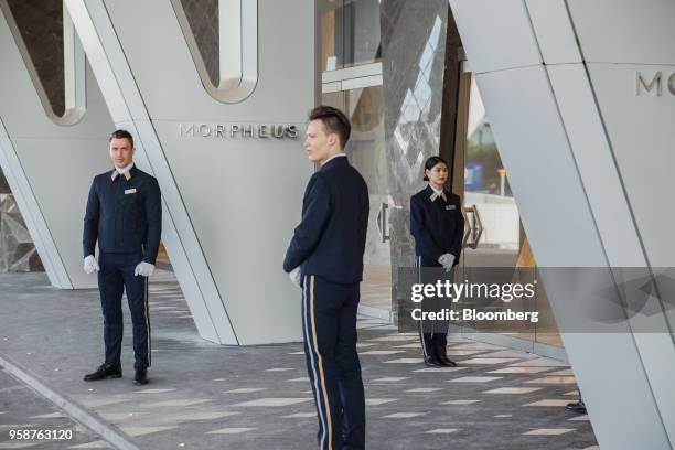 Porters stand outside the Morpheus hotel, developed by Melco Resorts & Entertainment Ltd., during a media tour in Macau, China, on Tuesday, May 15,...